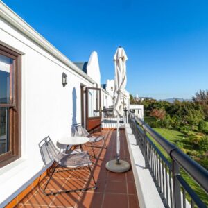 A balcony with two chairs and an umbrella at Winelands Golf Lodges 9 in Stellenbosch
