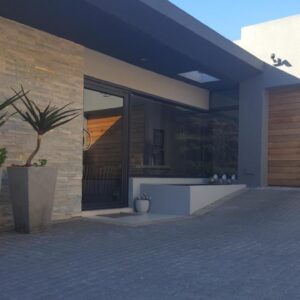 A house with two potted plants on the side of it at Yadah Guest House in Mossel Bay