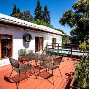 A deck with chairs and a table on a house at Zoete Inval Travelers Lodge Guesthouse Hermanus in Hermanus