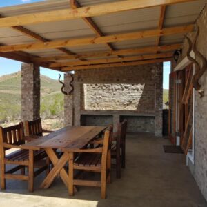 A wooden table and chairs on a patio at Zwartberg View Mountain Lodge in Oudtshoorn