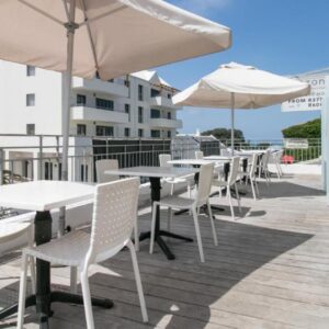 A patio with tables and umbrellas on a balcony at Zzzone Boutique Hostel in Hermanus