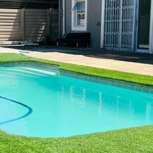 African Haven Guest House: a swimming pool with blue water in a yard