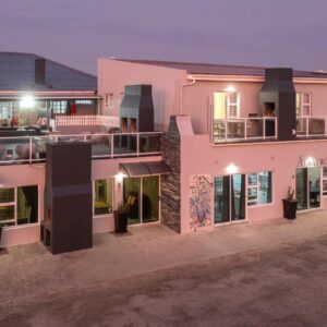 Albatross Accommodation: a large pink building with lights on