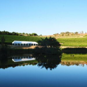 Alluvia Boutique Winery & Luxury Accommodation: a pond with a house in the middle of a field