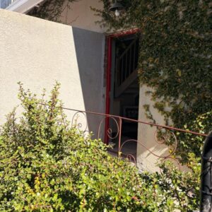Almond Cottage Bed & Breakfast: a building with a red door and some bushes