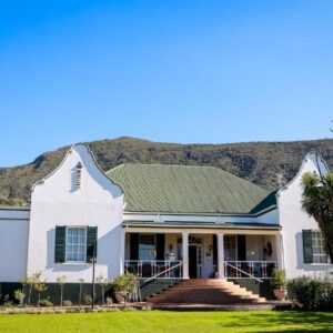 Altes Landhaus Country Lodge: a house with a palm tree and mountains in the background