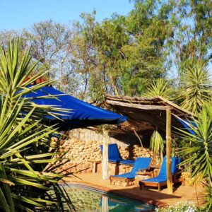 Amber Lagoon Eco Chalets, Rooms, Camping and Glamping: a resort with blue chairs and a swimming pool
