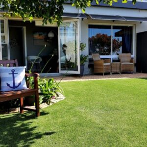 Amelia's by the Sea: a bench sitting on a lawn in front of a house