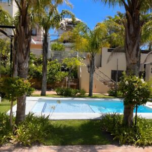 At Villa Fig Guest House: a swimming pool in front of a house with palm trees