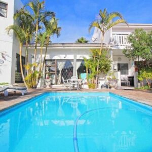 Au Plais De Langebaan at Palm Tree Villa: a large blue swimming pool in front of a house