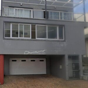 August Crest Accommodation: a building with two garage doors and a balcony
