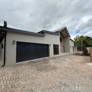 Autumn's Rest: a white house with a garage with a brick driveway