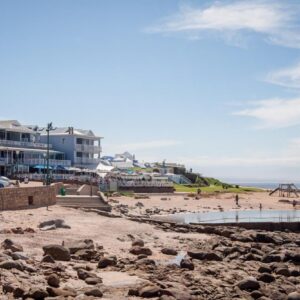 Barefoot Lodge, Mossel Bay: a beach with rocks and buildings and the ocean