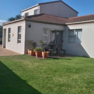 Bay Breeze Guesthouse Selfcatering: a house with a green lawn in front of it