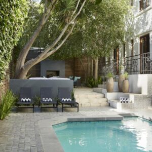 Bayflowers Guest House: a swimming pool in a yard with chairs next to a building