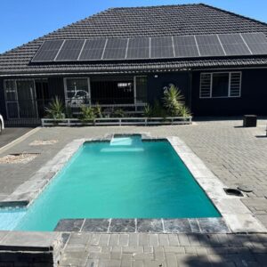 Bell rose oaks guest house: a swimming pool with solar panels on top of a house