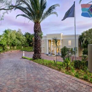 Bell Rosen Guest House: a palm tree in front of a building with flags