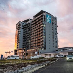 Blaauwberg Beach Hotel: a tall building with cars parked in front of it