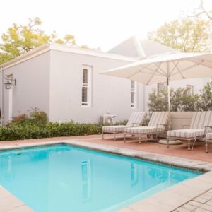 Bonne Esperance Studio Apartments: a pool with chairs and an umbrella next to a house