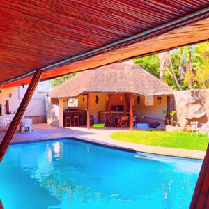 Budget Haven Durbanville: a house with a swimming pool with a thatch roof