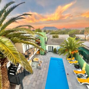 Cape Town 4U Guesthouse: an aerial view of a resort with a pool and palm trees