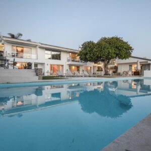 Capo Cabana Guesthouse: a large swimming pool in front of a house