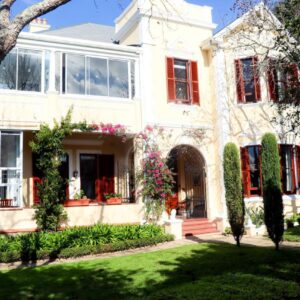 Carmichael House Boutique Hotel: a large white house with red shutters