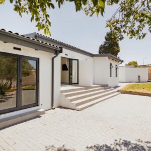 Catalyst Guest House: a white house with large windows and a patio
