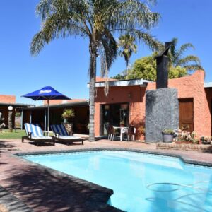 Culdesac Guesthouse Oudtshoorn: a swimming pool in front of a house