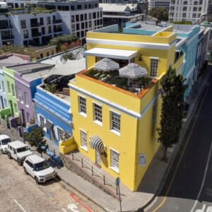 De Waterkant Place: a yellow building on a city street with parked cars