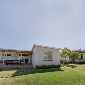 Dennehof Farm Guesthouse: a small white house with a grass yard