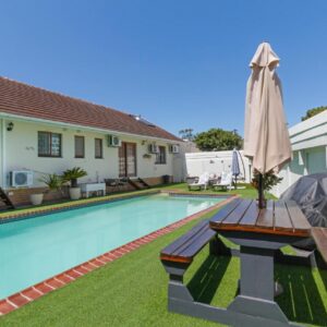 Dolliwarie Guesthouse: a swimming pool with an umbrella next to a house