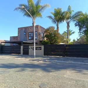 Earthbound Guest House: a house with a fence and a palm tree