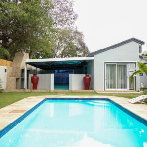 El-Gibor Best Guest House: a swimming pool with two lawn chairs and a house