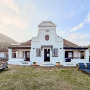 Far Niente Beachfront Guesthouse: a white house with two blue chairs in the yard
