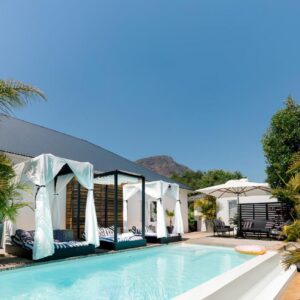 Franschhoek Maison du Cap: a pool with chairs and umbrellas next to a house