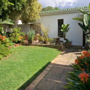 Haus Barbara Guest House: a garden with a white house with a lawn