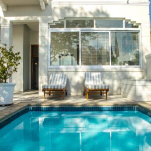 Head South Lodge: a swimming pool with two chairs next to a house