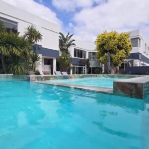 Hermanus Manor: a large swimming pool with blue water in front of a building