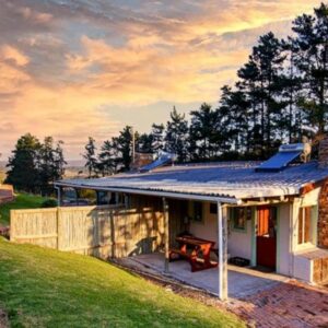 Hermanuspietersfontein Cottages: a stone house with a bench in front of it