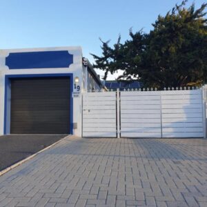 Hibiscus B&B: a building with a garage with a white fence