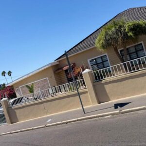 Home of peace self catering accommodation: a building with a fence and an arrow on the street