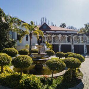 Homestead Villas: a garden with a fountain and bushes in front of a house