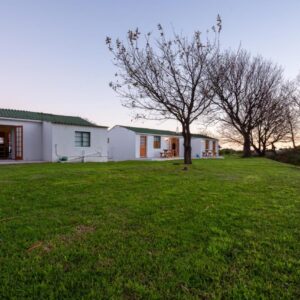 Honeyrock Cottages: a white house with a green lawn in front of it