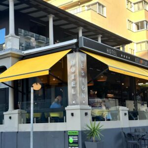 Hotel on the Promenade: a restaurant with a yellow umbrella in front of a building