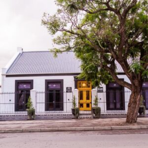 House of Pinardt: a white house with a yellow door and a tree