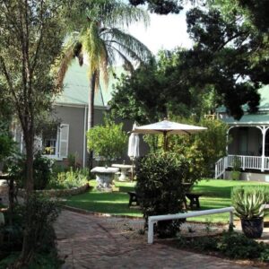 HouseMartin Lodge & Self Catering: a house with a garden with a table and an umbrella