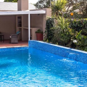 Julinas Guesthouse: a blue swimming pool in front of a house