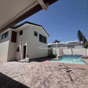 Kabana Family Home and Guest House: a house with a swimming pool and an umbrella