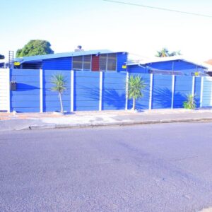 Kitty Guest House: a blue building with palm trees in front of a street